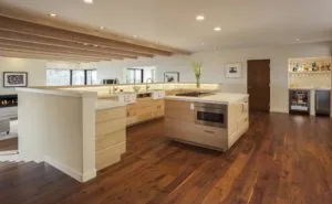 Modern kitchen with light wood cabinetry, large island, stainless steel appliances, and hardwood flooring