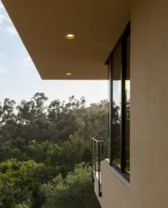 Modern architectural overhang with recessed lighting overlooking forested hillside landscape