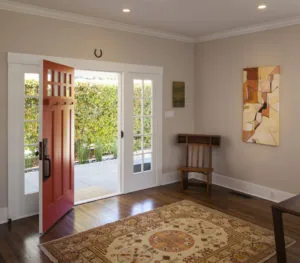 Modern entryway with red front door, glass patio doors, wooden flooring, and traditional area rug