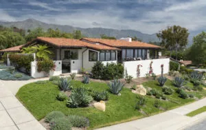 Modern white and terracotta residential home with manicured lawn, desert landscaping, and mountains in background