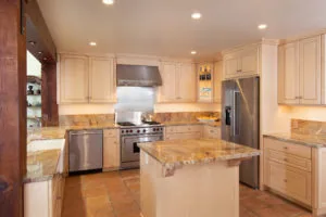 Modern kitchen with light wood cabinetry, granite countertops, stainless steel appliances, and center island with seating area