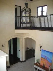 Two-story foyer with arched doorways, wrought iron railings, pendant lantern, and decorative wall sconces