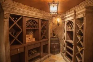 Rustic wood wine cellar with diamond-pattern glass cabinet doors, wooden wine racks, barrel, and vintage lighting fixtures