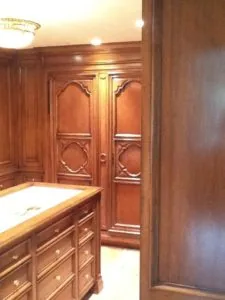 Traditional wood closet interior with ornate double doors and matching vanity cabinet with white countertop