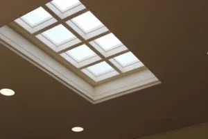 Ceiling skylight with grid of eight illuminated panes above recessed lighting fixtures