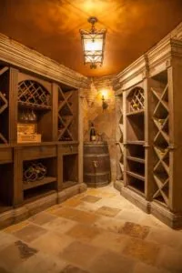 Elegant wine cellar with wooden lattice cabinets, barrel, pendant light, and stone flooring.