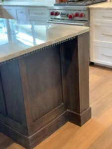 Kitchen island with dark wood base and light countertop, white cabinetry visible in background