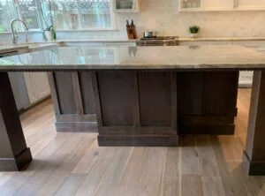 Modern kitchen island with dark wood base and light countertop, featuring sink and seating area