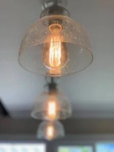 Pendant light fixture with clear glass shade and glowing filament bulb suspended from ceiling