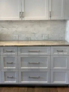 Modern kitchen with white cabinetry, marble subway tile backsplash, quartz countertop, and stainless steel hardware